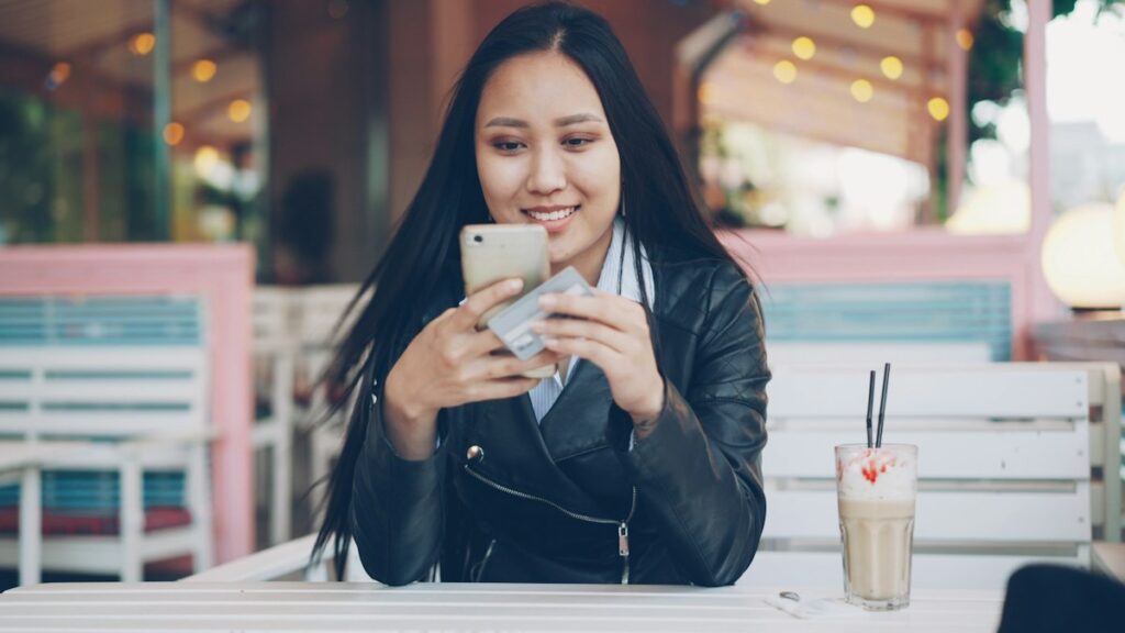 Mulher usando smartphone em café, ilustrando a bio para Instagram de advogado