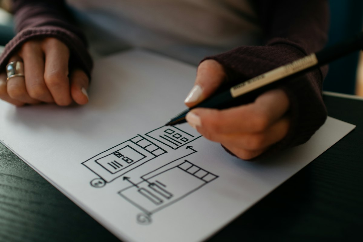Pessoa esboçando layout em papel, ilustrando construtores de landing page para advogados