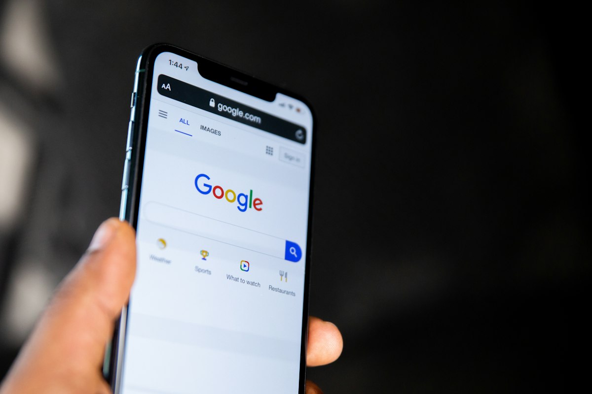 Mão segurando smartphone com a busca do Google, ilustrando Google Meu Negócio para advogados
