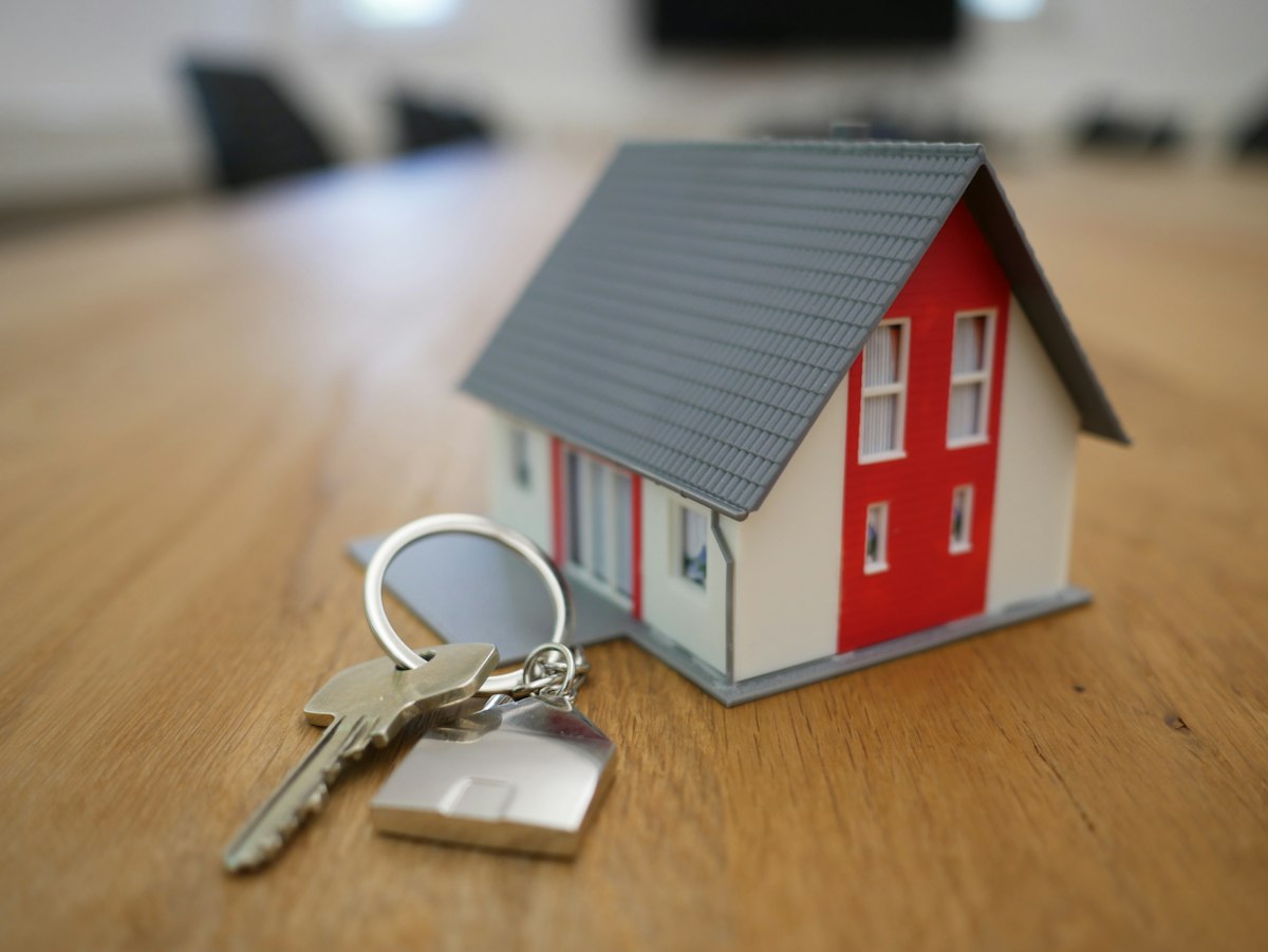Miniatura de casa e chaves, ilustrando marketing para advogado imobiliário