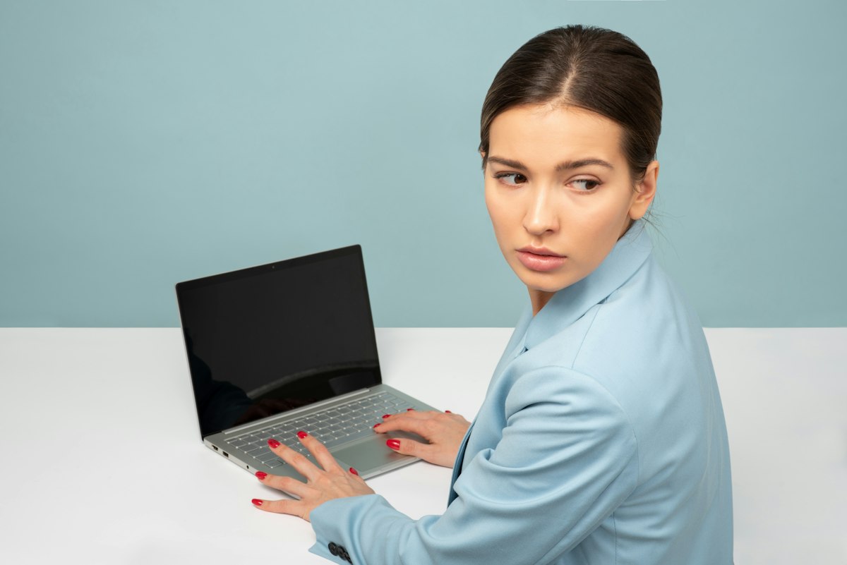 Mulher usando laptop e olhando para o lado, ilustrando meu escritório não aparece no Google