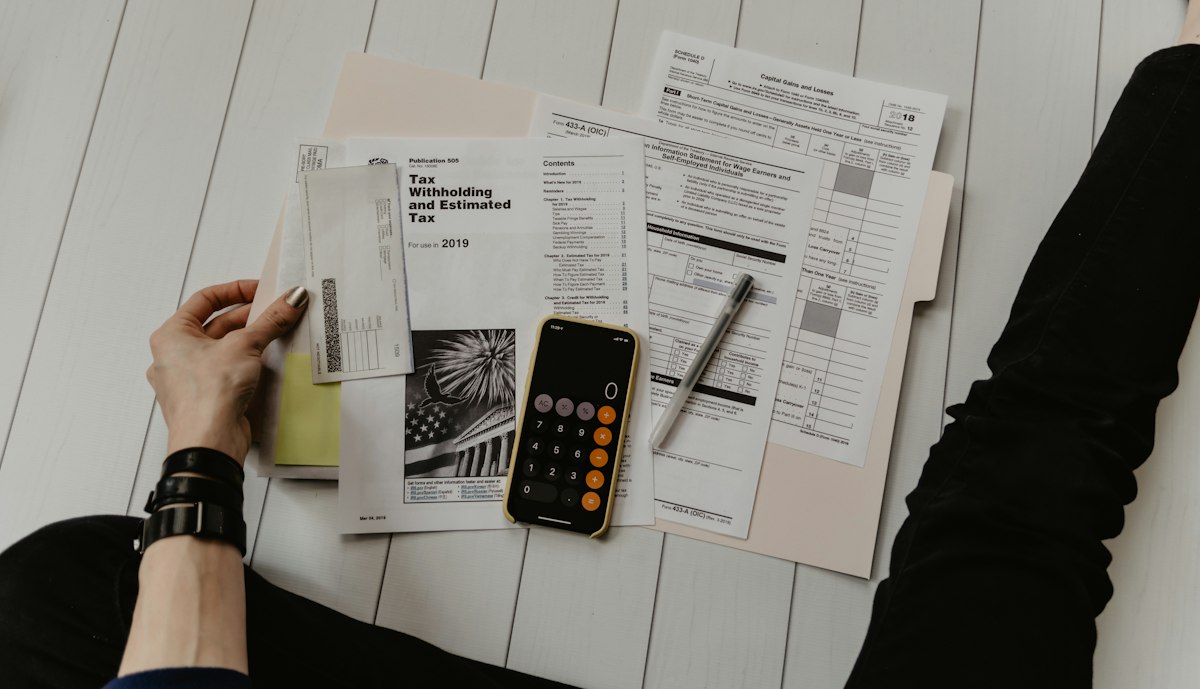 Pessoa segurando papel perto de caneta e calculadora, ilustrando quanto investir em marketing jurídico